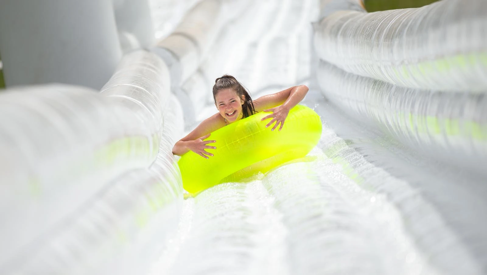 woman on yellow tube coming down inflatable water slide